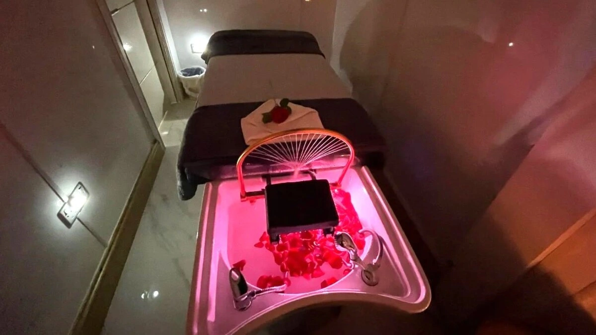 Innenraum eines gemütlichen, gedämpft beleuchteten Japanese-Head-Spa-Raums mit einer Behandlungsliege, einem Waschbecken mit Blütenblättern und Spa-Ausstattung