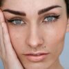 Nahaufnahme des Gesichts einer Frau mit Microblading an den Augenbrauen, natürlichem Make-up und hochgestecktem dunklem Haar
