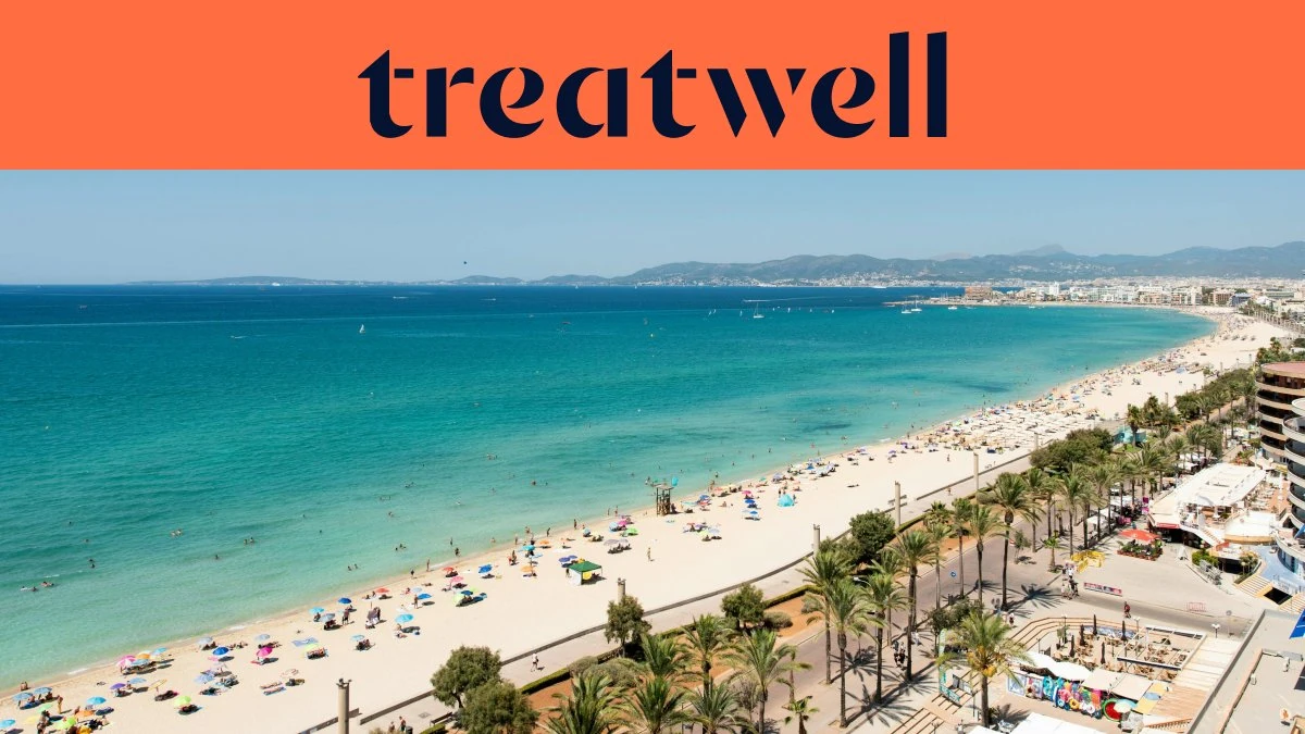Luftaufnahme der Playa de Palma auf Mallorca, mit einem langen, geschwungenen Streifen goldenen Sandes, Reihen von Sonnenschirmen, ruhigem türkisfarbenem Wasser und einer palmengesäumten Promenade entlang der Stadt, mit Hügeln in der Ferne unter klarem blauem Himmel.
