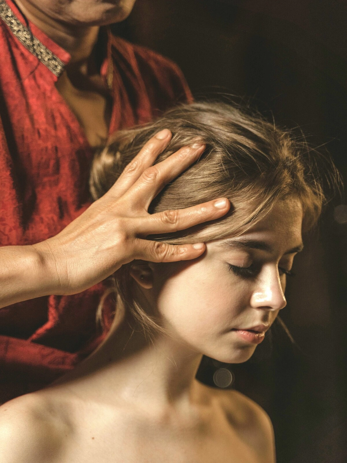 Nahaufnahme einer Frau mit geschlossenen Augen, während eine Fachkraft bei einer indischen Kopfmassage ihre Kopfhaut massiert